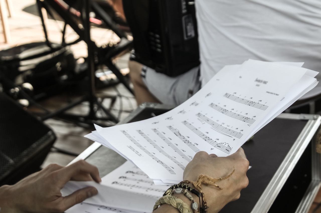 Plagio musicale: Primo piano delle mani di un musicista con spartiti durante una prova in uno studio
