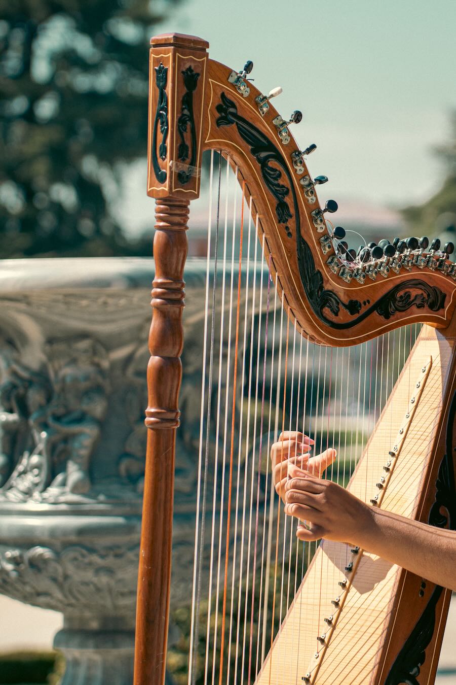 Un musicista suona un'arpa tradizionale all'aperto in un giardino soleggiato di Madrid, in Spagna. L'arpa è davvero uno strumento classico